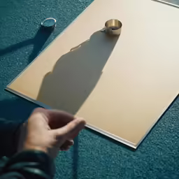 person pointing to a board with a tiny ring on it