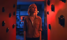 a woman is standing in front of the bright red light of a room