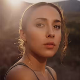 a close up photo of a woman with a tan eye make - up and the sun shining on her face