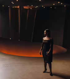 a woman in black dress standing in front of an abstract room
