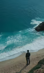 the man is staring down at the ocean