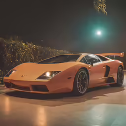 an orange sports car parked in a parking lot at night