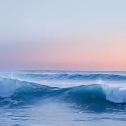 a couple of ocean waves in the middle of sunset