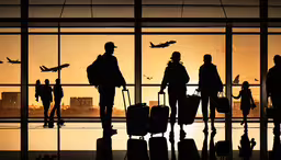 the silhouette of passengers in front of an airport window at sunset,an airport with people and luggage standing outside