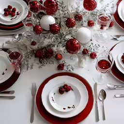 a white and red table setting on white tablecloth