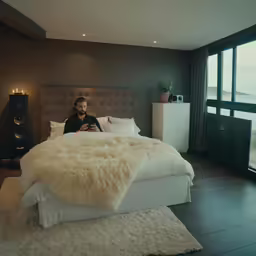 the man is posing for a picture while sitting on a bed