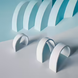 three circular, white sculptures on gray surface