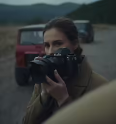 a woman holding a camera while looking in the mirror