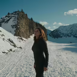 a woman standing in snow next to mountains