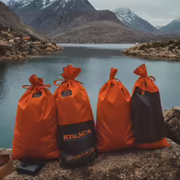 three orange bags with logo sitting on a rock