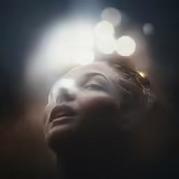 a woman looking up at bright lights in the distance