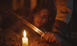 a woman is holding two sword standing in the dark