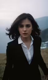 a woman in black jacket holding hands with mountain and sea in background