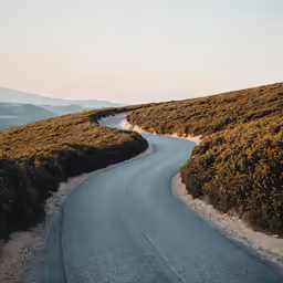 a curved road going through green hills
