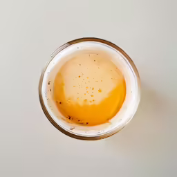 a glass filled with water and liquid on top of a white surface