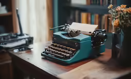 a blue typewriter sitting next to an old fashioned typewriter on a desk