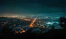 an aerial view of a city at night, with street lights in the foreground and mountains in the back