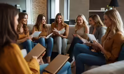 a group of young women gathered around a couch talking