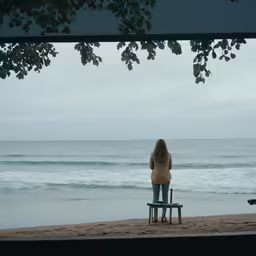 a person standing on top of a bench near the ocean