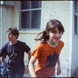 the young girl is running toward the camera with her friend