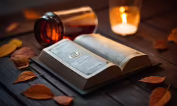 a book on a table next to a lit candle