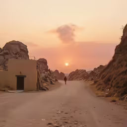 the person walking down the road in front of a rocky outcropping
