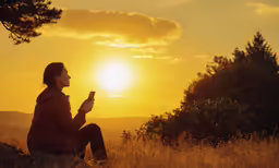 woman sitting outdoors on grassy area in front of a sunset