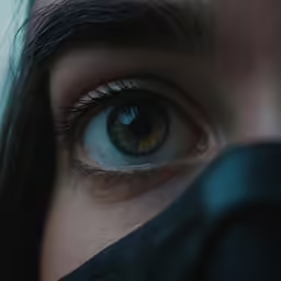 an eye is shown looking down, with a black object below the eyes