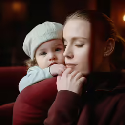 a mother hugging her child as he stares at the camera