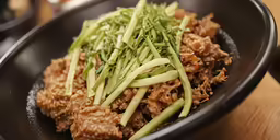 a black bowl is filled with food and greens