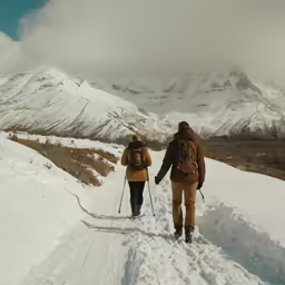 two people walking up hill on skis in snow