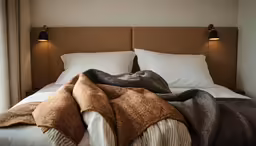 a bedroom with white and brown colors and pillows