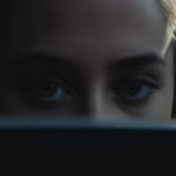 a woman looks through her laptop with very big blue eyes