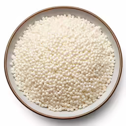 a bowl filled with white tiny beads on a table