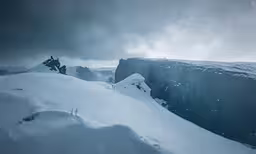 a cliff covered in snow and surrounded by lots of dark clouds