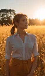 woman standing in field at sunset with sun shining through