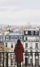a woman in a red coat is standing on a balcony