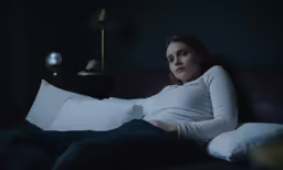 a pregnant woman laying on a bed with pillows and pillows