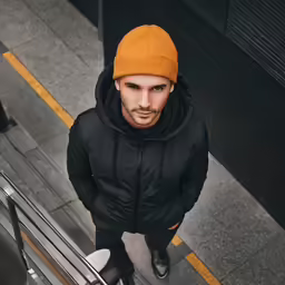 the man is wearing an orange hat and black jacket