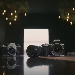 two cameras sitting on a table with lights hanging overhead
