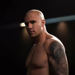 a man with a large bald head and tattoos standing