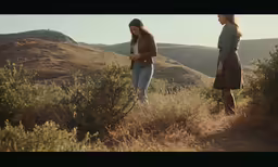 two women walk up a hill to look at something