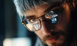 a man with long hair and glasses looking into the distance