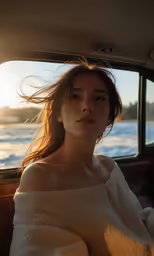 a woman with long hair sitting in the back seat of a car looking out at water