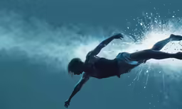 a person falling underwater in the blue water