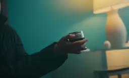 someone holds a camera in their hand near a lamp
