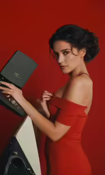 a young woman holding a speaker in front of a red background