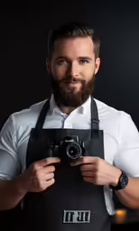 a man wearing a black apron holding a camera