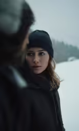 a woman wearing a black hat and coat in the snow