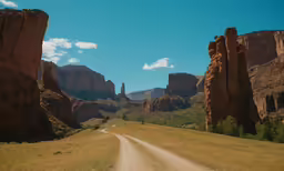 a gravel road leading into some tall rocky formations
